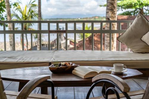 a table with a book and a cup of coffee on a balcony at Bombora Medewi in Pulukan