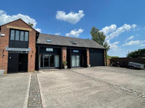 ein Backsteingebäude mit einer Einfahrt davor in der Unterkunft Fernside Barn - Studio Apartment in Pickmere