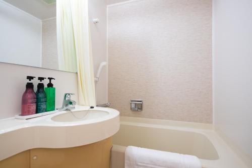 a bathroom with a sink and a mirror at 鹿島アイビーホテル in Fukashiba