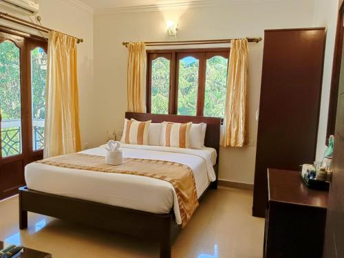 1 dormitorio con 1 cama grande frente a las ventanas en Goa Villagio Resort & Spa - A unit of IHM, en Betalbatim