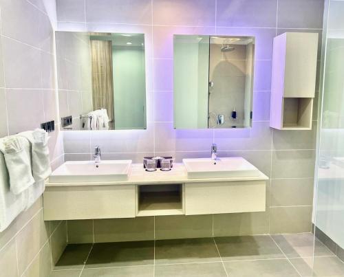a bathroom with two sinks and a mirror at The Bay Sunflower Apartment in Nusa Dua