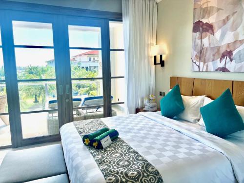 a bedroom with a bed and a large window at The Bay Sunflower Apartment in Nusa Dua