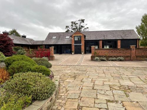 ein großes Haus mit einer steinernen Einfahrt davor in der Unterkunft Fernside Barn - Studio Apartment in Pickmere