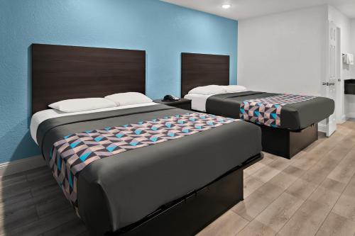 Duas camas num quarto com paredes azuis em Rodeway Inn em Palestine