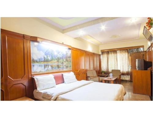 a bedroom with a bed and a large window at Hotel Valley View, Mussoorie in Mussoorie