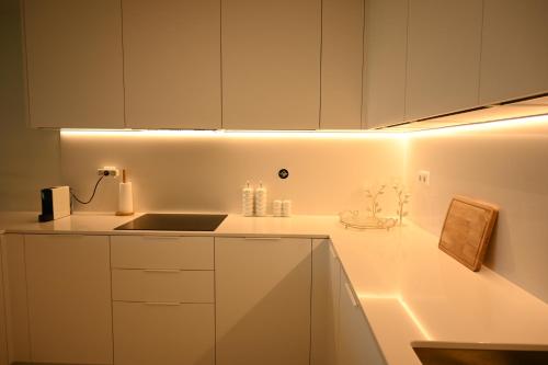 a kitchen with white cabinets and a sink and lights at BaySun Apartment & SPA - Bayline in Armação de Pêra