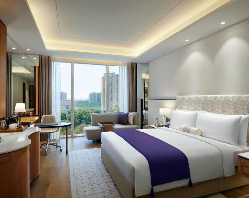 a bedroom with a large bed and a living room at The Leela Bhartiya City Bengaluru in Bangalore
