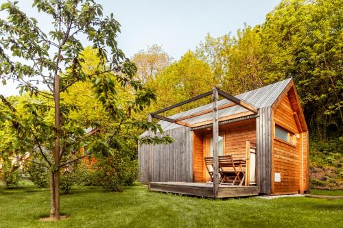 a small cabin with a deck and chairs in a yard at Glamping Mountain Fairy Tale in Bistrica pri Tržiču