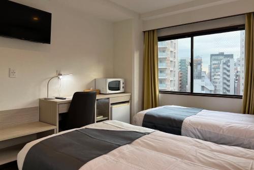 um quarto de hotel com 2 camas e uma secretária com um micro-ondas em Le Tour Hotel Akihabara Kandai 楽途ホテル神田秋葉原 em Tóquio