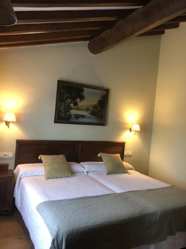 a bedroom with two beds and a painting on the wall at Casa Rural Trebol4Hojas in San Pedro