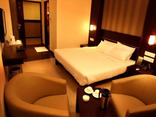 een hotelkamer met een bed en een stoel bij SUNFLOWER HOTEL in Mysore