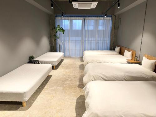 uma fila de camas num quarto com lençóis brancos em Hotel art rock em Takamatsu