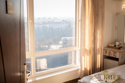a bedroom with a window with a view of a city at Hotel Kiev in Veliko Tŭrnovo