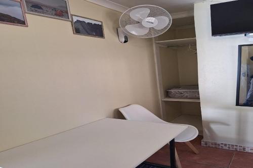 a room with a white table and a fan at Maluti Backpackers in Phuthaditjhaba