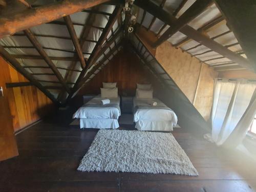 two beds in a attic room with a rug at Rain Farm Game Lodge in uMhlali