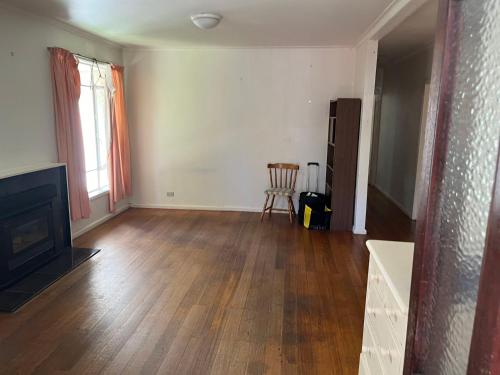 an empty living room with a fireplace and wooden floors at 12 Olive Cozy Rooms in Frankston