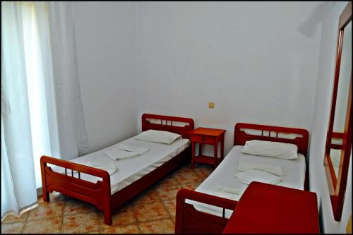 two beds in a room with two red chairs at Studios & Appartments Posidonio in Klíma