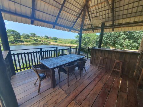 a table on a deck with a view of a river at Rain Farm Game Lodge in uMhlali