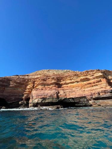 a cliff in the ocean next to the water at Manta Stays in Kalbarri