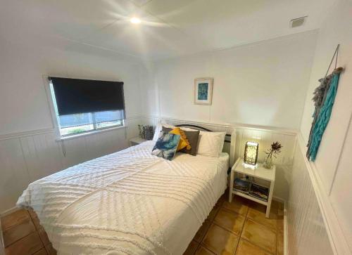 a white bedroom with a bed and a window at Manta Stays in Kalbarri