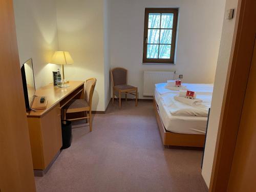 a room with a bed and a desk with a desk at Landhotel Der Distelhof mit Scheunencafé in Dillstädt