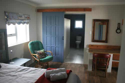 1 dormitorio con cama, silla y escritorio en House of 2 Oceans, en Agulhas