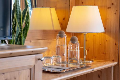 a table with a lamp and glasses on it at Hotel Canova Sport & Relax in Cavaso del Tomba