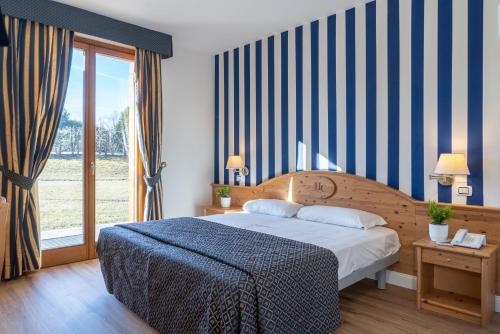 a bedroom with a bed with a blue and white striped wall at Hotel Canova Sport & Relax in Granigo