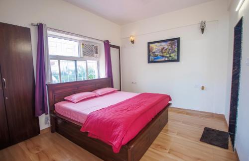 een slaapkamer met een bed met roze lakens en een raam bij PARADISE VILLA in Lonavala