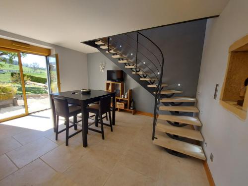 a dining room with a table and a spiral staircase at Gite Stone & Spa in Chasselay