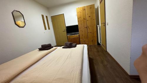 a bed in a room with two shoes on it at Pension Restaurant Pizzeria Lion in Krummhörn