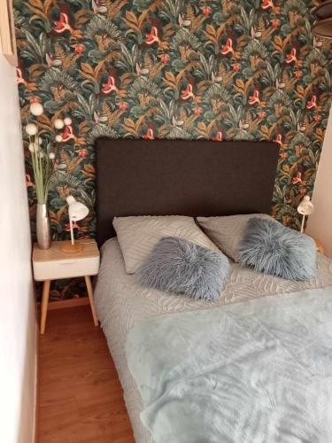 a bed with two pillows in front of a floral wall at DANTIN laurent in Le Crotoy