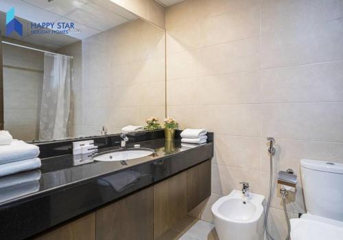 een badkamer met een wastafel, een toilet en een spiegel bij Luxurious 2BR Apartment near Palm Jumeirah in Dubai