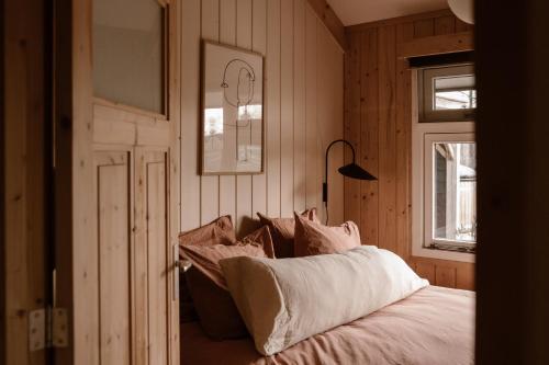 1 dormitorio con cama con almohadas y ventana en Getaway - Farm House + hottub en Nistelrode