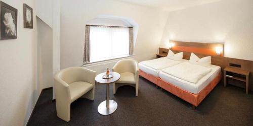 クックスハーフェンにあるHotel Gasthof Zur Postのベッド、テーブル、椅子が備わるホテルルームです。