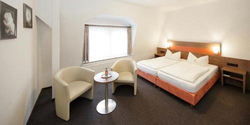 ein Hotelzimmer mit einem Bett und einem Tisch und Stühlen in der Unterkunft Hotel Gasthof Zur Post in Cuxhaven