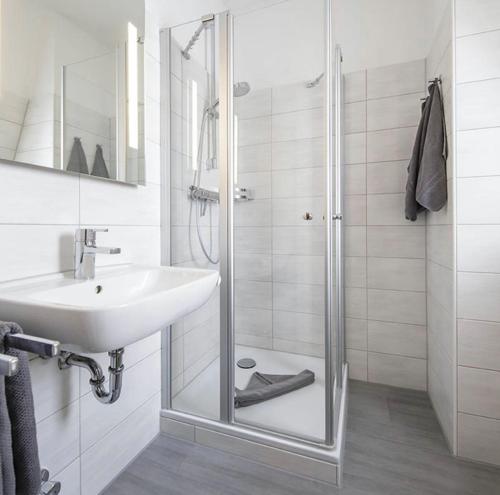 ein Bad mit einer Glasdusche und einem Waschbecken in der Unterkunft Hotel Gasthof Zur Post in Cuxhaven