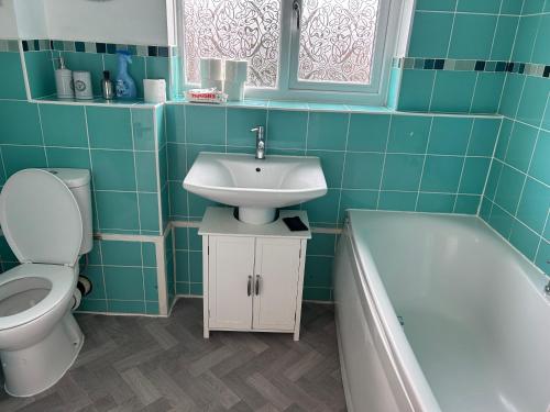 a bathroom with a sink and a toilet and a tub at Spacious family home in Malins Lee