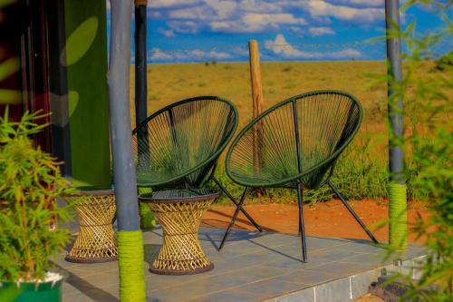 two chairs sitting on a porch with a field in the background at Amanya 3-Bedroom Hut Amboseli in Amboseli