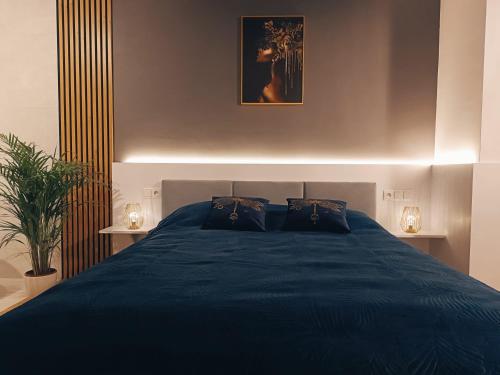 a bedroom with a blue bed with two lamps at Apartamenty Centrum in Janów Lubelski