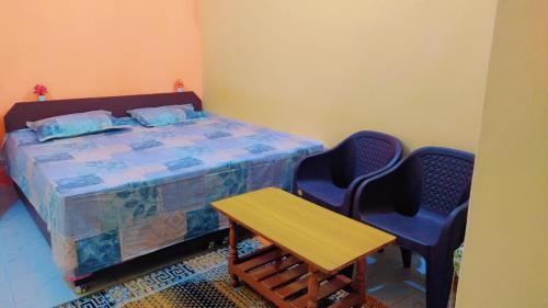 Schlafzimmer mit einem Bett mit 2 Stühlen und einem Tisch in der Unterkunft Mahavir Home Stay in Ujjain