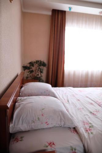 a bed with two pillows on it with a window at Котедж у Карпатах in Tukholʼka