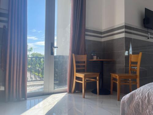 a bedroom with a bed and two chairs and a table at VIEW HOTEL- TRÀM CHIM in Tràm Chim