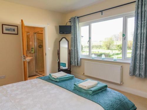 een slaapkamer met een bed met een spiegel en een raam bij Two Acres- Spacious, delightful, pet free bungalow in Levens