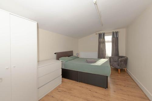 a bedroom with a bed and a chair and a mirror at Cosy 4 bedrooms house near Central London, O2, London city airport and Excel in Plumstead