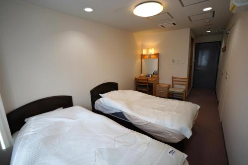 白馬村にあるThe Hakuba Station Roomのベッド2台、テーブル、椅子が備わる客室です。