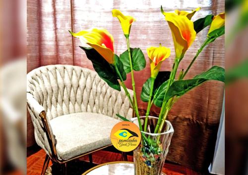 Un jarrón con flores junto a una silla. en GuestHouse Pombinha en Nazaré