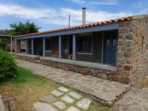 a stone house with a porch and a stone wall at To Spitaki House in Perdika
