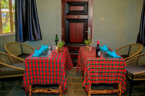 two tables in a restaurant with two bottles of wine at Amanya 3-Bedroom Hut Amboseli in Amboseli