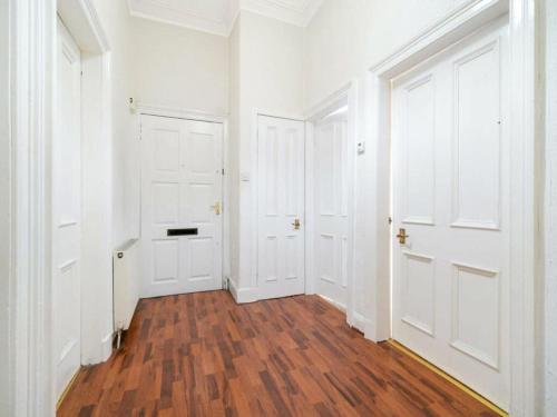 an empty hallway with white doors and wooden floors at Glasgow road in Glasgow